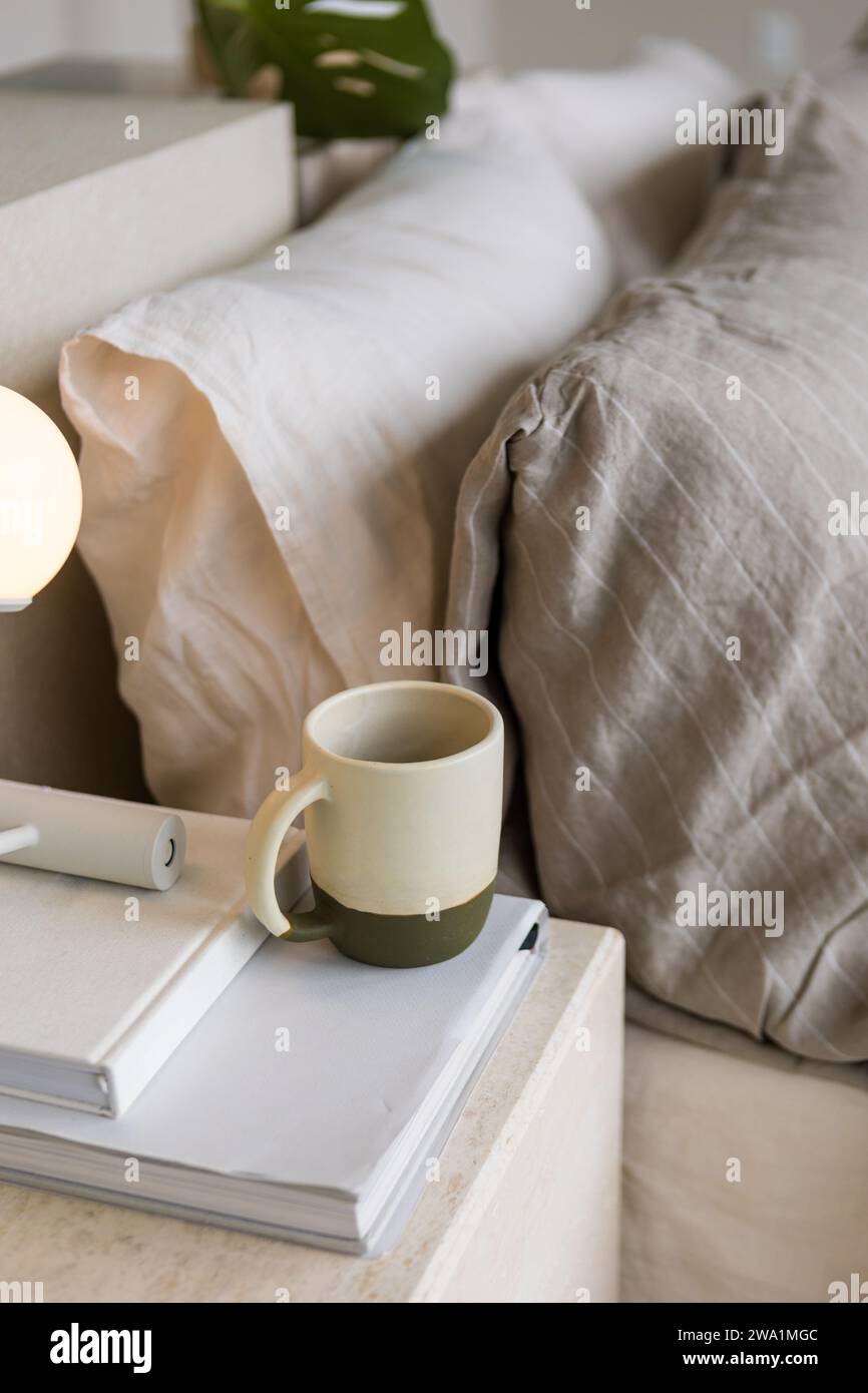 Tazza in ceramica sopra i libri di un letto estetico crea una scena tranquilla Foto Stock