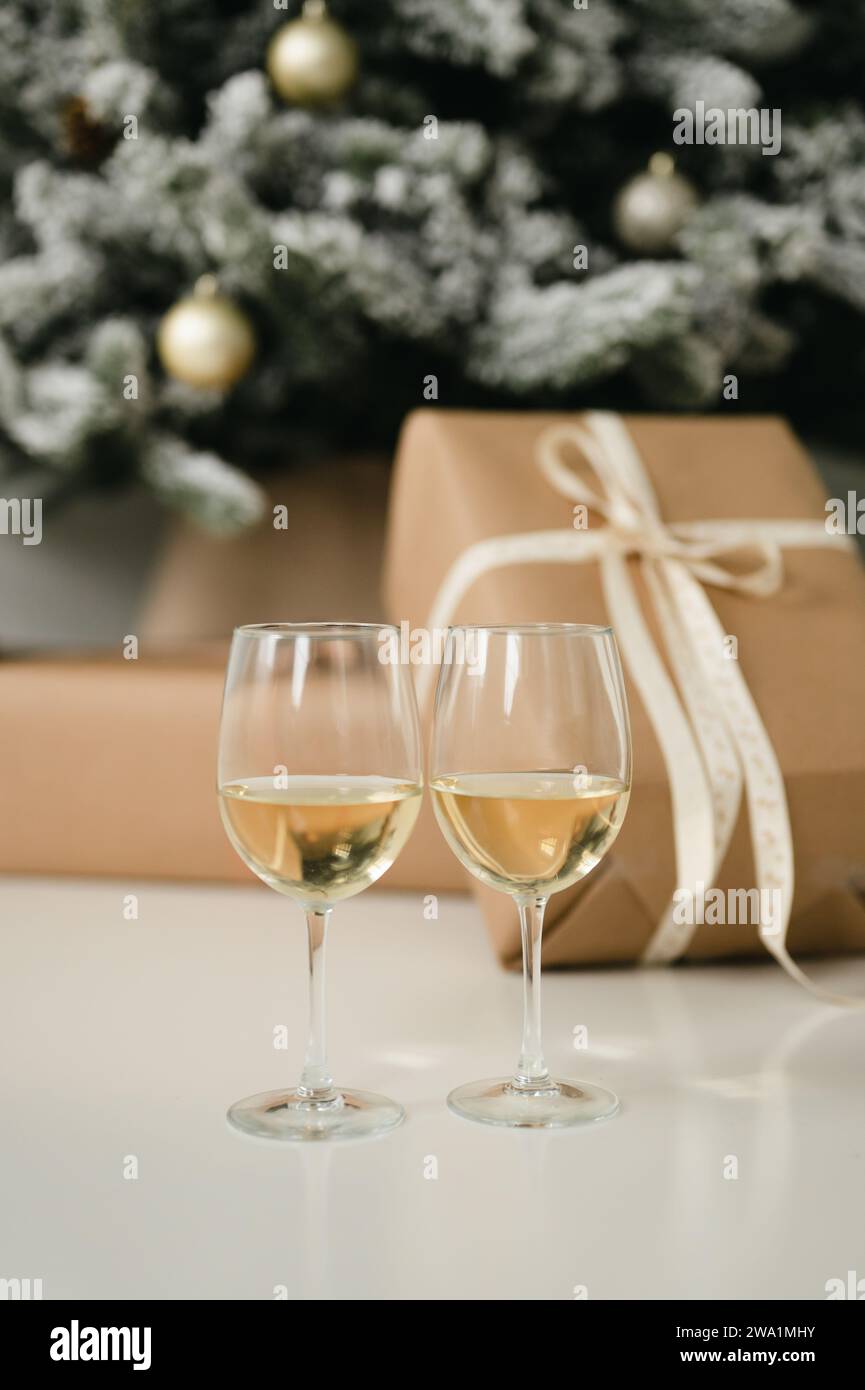 Due bicchieri da vino davanti a un albero di natale con regali Foto Stock