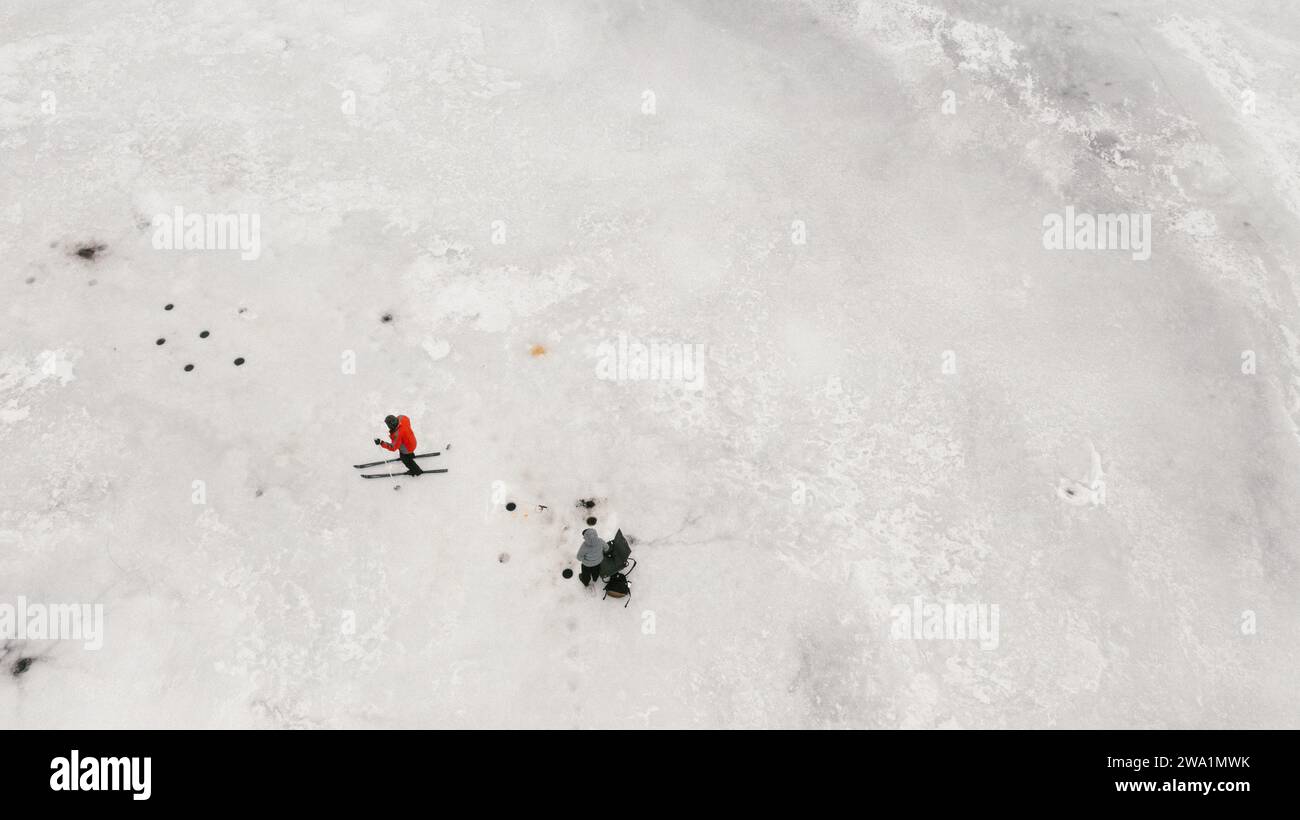Sciatore di fondo con pescatori di ghiaccio sul lago ghiacciato in inverno Foto Stock