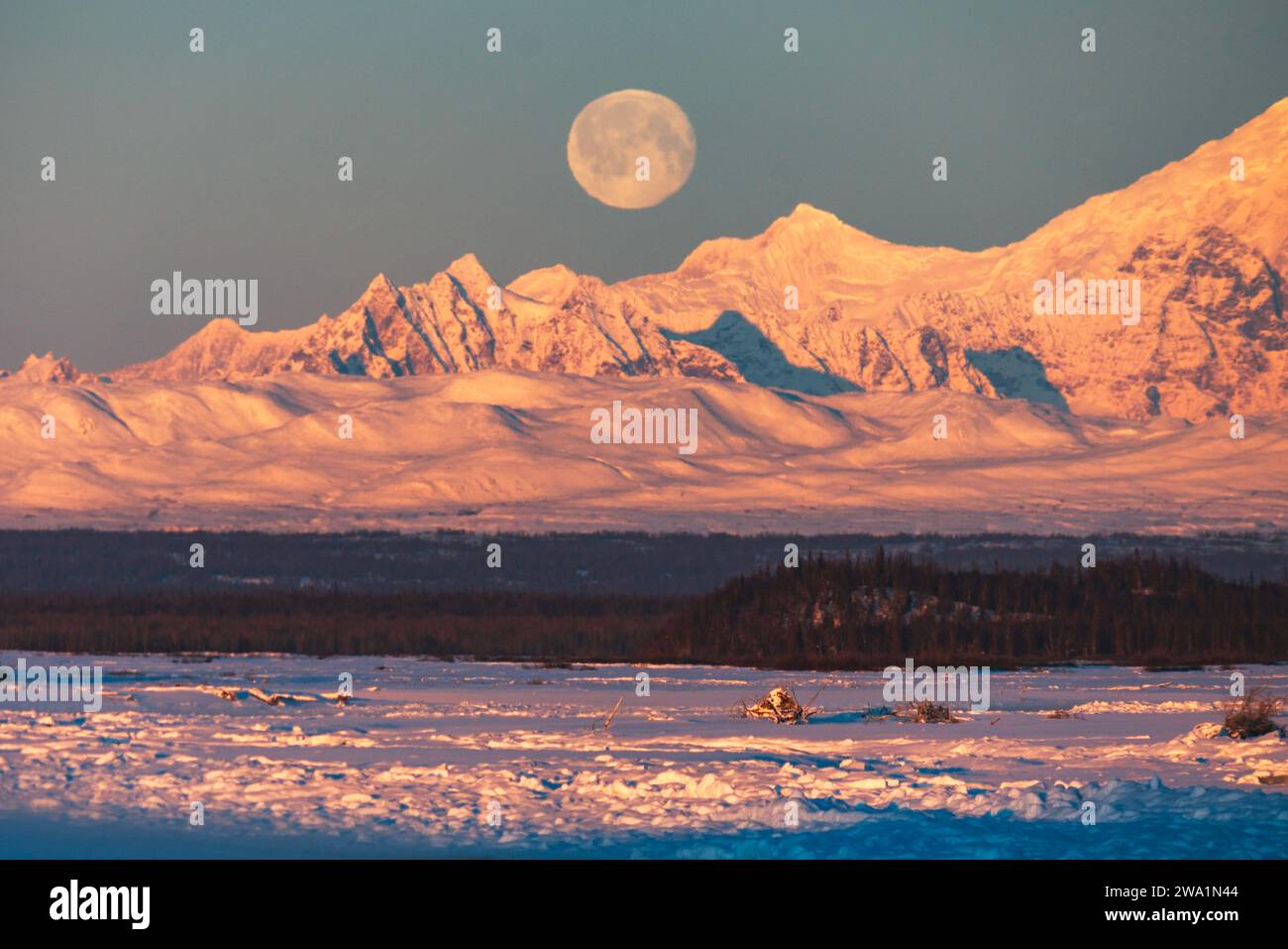 La luna piena sorge dietro la catena montuosa dell'Alaska con il monte Foraker Foto Stock