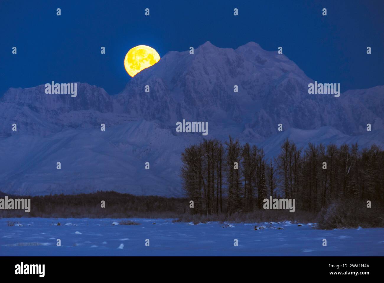 La luna piena sorge dietro il monte Hunter e la catena montuosa dell'Alaska Foto Stock
