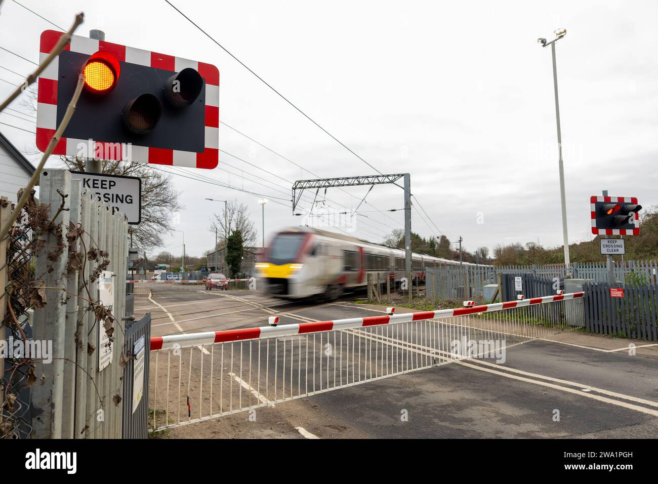 Un treno ad alta velocità della grande Anglia passa un passaggio a livello chiuso a Great Blakenham Claydon, Ipswich, Suffolk, dicembre 2023 Foto Stock