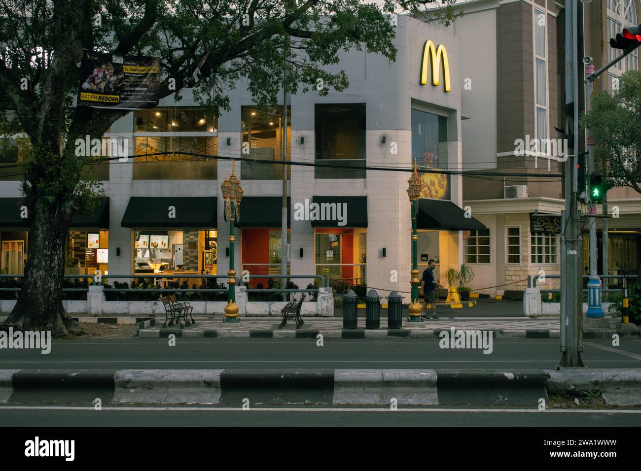 Malang, Indonesia, 1 gennaio 2024: Un uomo cammina davanti al McDonald's vicino al semaforo rosso di Kayutangan Street, Malang, Giava Orientale. Foto Stock