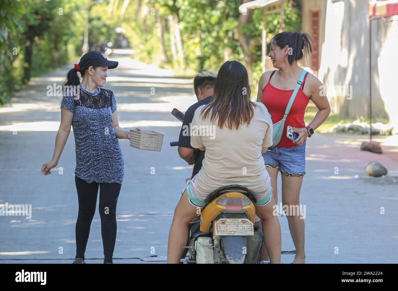 Tiaong, Filippine. 1 gennaio 2024: Nelle province rurali, le famiglie povere filippine costruiscono strade a pedaggio amichevoli con una corda e un cartello di felice anno nuovo. Auto, tricicli o pedoni sono incoraggiati a fare donazioni "grazie", generalmente solo pochi pesos, senza impegno, sempre con sorriso e talvolta abbelliti da pochi passi di danza. Una tradizione che era praticata solo in alcune regioni e che si è diffusa in quasi tutto il paese dai giorni duri dell'epidemia di COVID 19. Ad esempio, oltre 1 km, in alcuni luoghi è possibile contare fino a quindici fermate. Crediti: Kevin Izorce/Alamy Live News Foto Stock