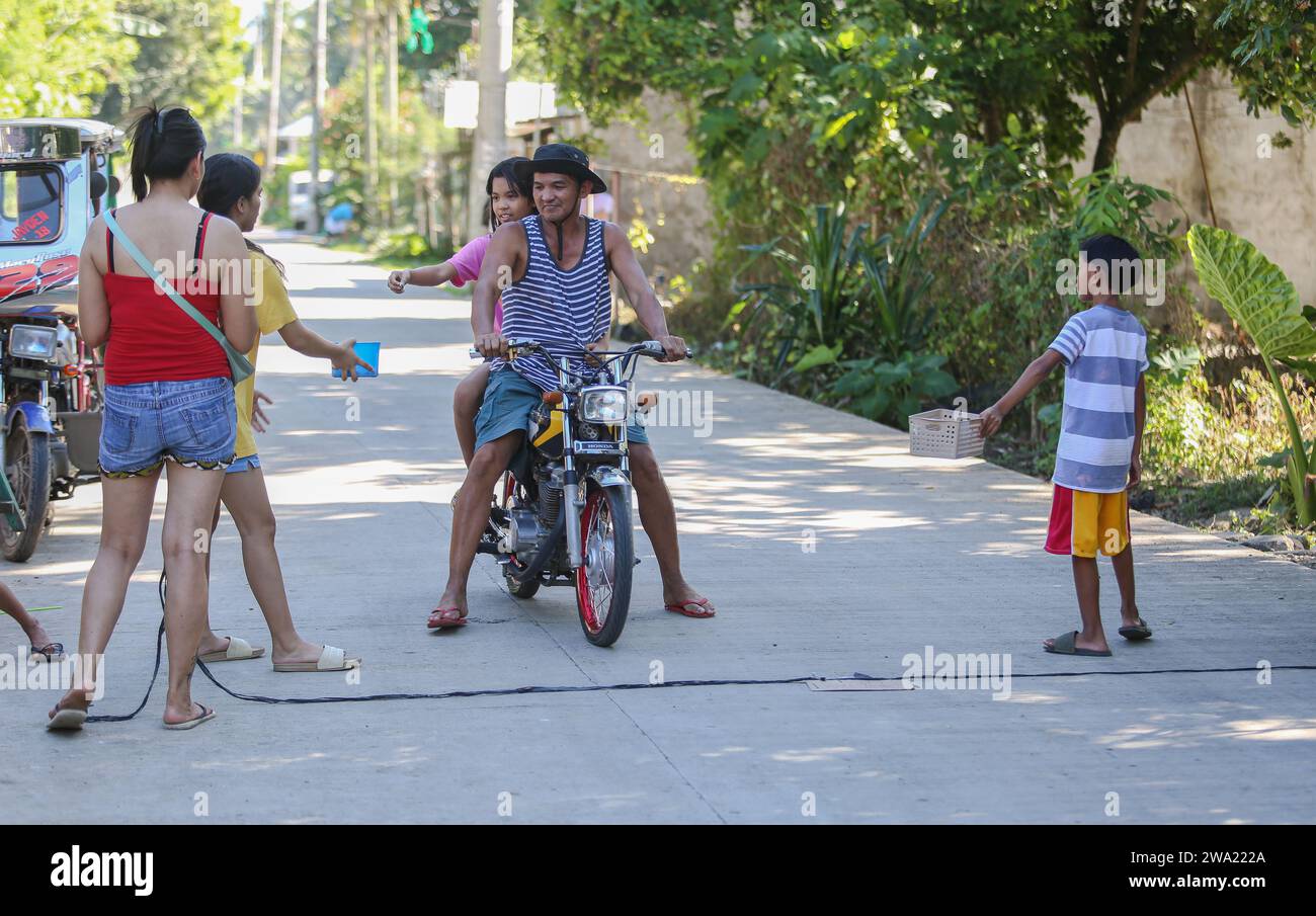 Tiaong, Filippine. 1 gennaio 2024: Nelle province rurali, le famiglie povere filippine costruiscono strade a pedaggio amichevoli con una corda e un cartello di felice anno nuovo. Auto, tricicli o pedoni sono incoraggiati a fare donazioni "grazie", generalmente solo pochi pesos, senza impegno, sempre con sorriso e talvolta abbelliti da pochi passi di danza. Una tradizione che era praticata solo in alcune regioni e che si è diffusa in quasi tutto il paese dai giorni duri dell'epidemia di COVID 19. Ad esempio, oltre 1 km, in alcuni luoghi è possibile contare fino a quindici fermate. Crediti: Kevin Izorce/Alamy Live News Foto Stock