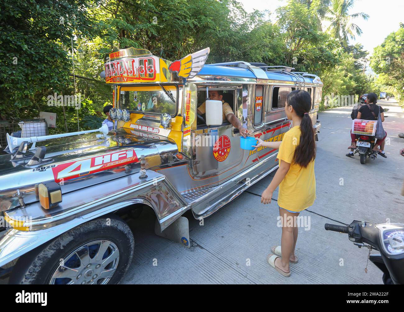 Tiaong, Filippine. 1 gennaio 2024: Nelle province rurali, le famiglie povere filippine costruiscono strade a pedaggio amichevoli con una corda e un cartello di felice anno nuovo. Auto, tricicli o pedoni sono incoraggiati a fare donazioni "grazie", generalmente solo pochi pesos, senza impegno, sempre con sorriso e talvolta abbelliti da pochi passi di danza. Una tradizione che era praticata solo in alcune regioni e che si è diffusa in quasi tutto il paese dai giorni duri dell'epidemia di COVID 19. Ad esempio, oltre 1 km, in alcuni luoghi è possibile contare fino a quindici fermate. Crediti: Kevin Izorce/Alamy Live News Foto Stock
