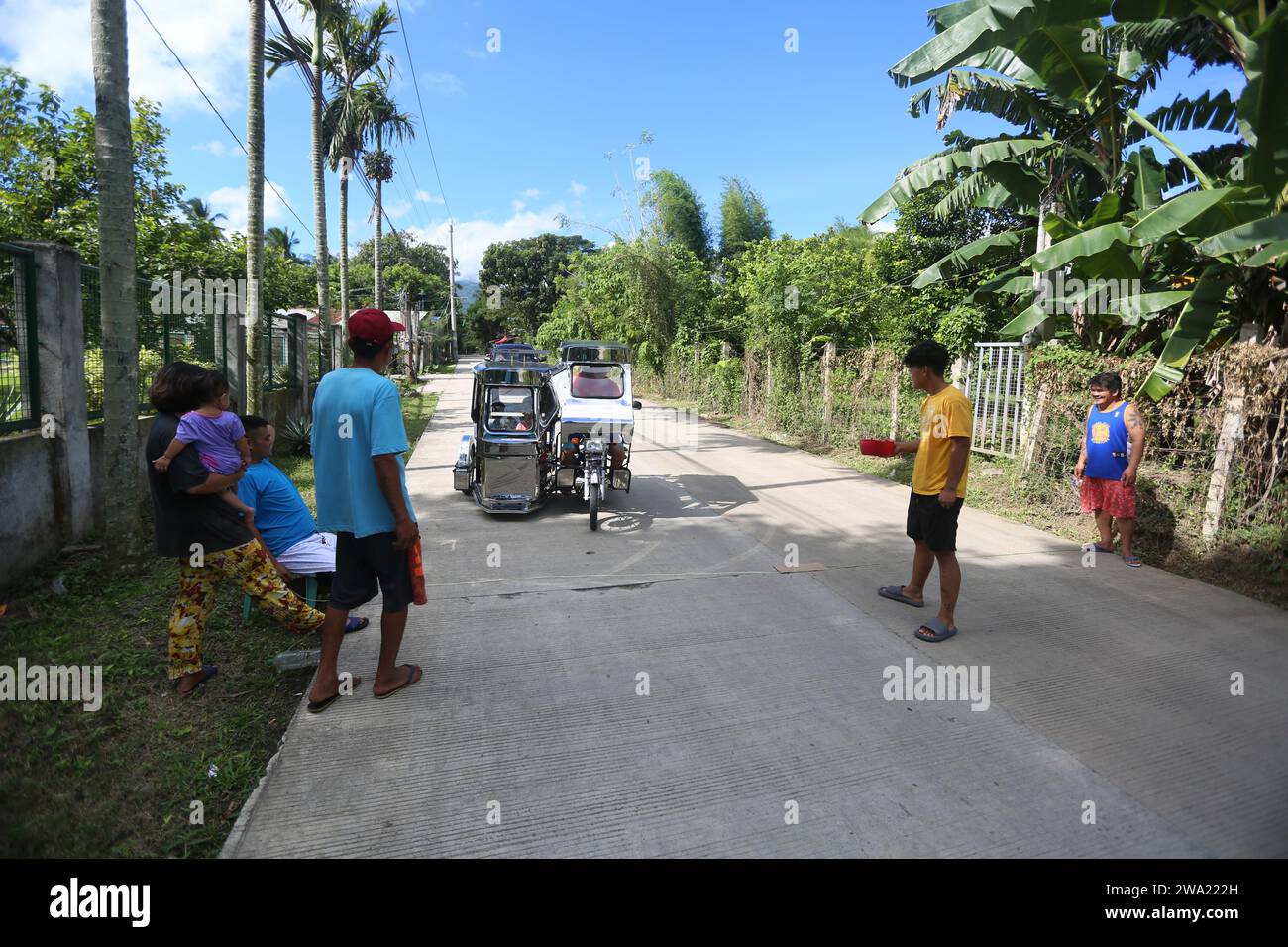 Tiaong, Filippine. 1 gennaio 2024: Nelle province rurali, le famiglie povere filippine costruiscono strade a pedaggio amichevoli con una corda e un cartello di felice anno nuovo. Auto, tricicli o pedoni sono incoraggiati a fare donazioni "grazie", generalmente solo pochi pesos, senza impegno, sempre con sorriso e talvolta abbelliti da pochi passi di danza. Una tradizione che era praticata solo in alcune regioni e che si è diffusa in quasi tutto il paese dai giorni duri dell'epidemia di COVID 19. Ad esempio, oltre 1 km, in alcuni luoghi è possibile contare fino a quindici fermate. Crediti: Kevin Izorce/Alamy Live News Foto Stock