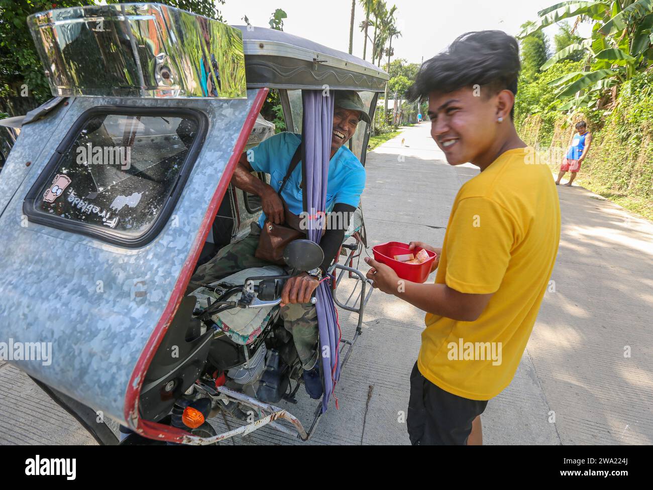 Tiaong, Filippine. 1 gennaio 2024: Nelle province rurali, le famiglie povere filippine costruiscono strade a pedaggio amichevoli con una corda e un cartello di felice anno nuovo. Auto, tricicli o pedoni sono incoraggiati a fare donazioni "grazie", generalmente solo pochi pesos, senza impegno, sempre con sorriso e talvolta abbelliti da pochi passi di danza. Una tradizione che era praticata solo in alcune regioni e che si è diffusa in quasi tutto il paese dai giorni duri dell'epidemia di COVID 19. Ad esempio, oltre 1 km, in alcuni luoghi è possibile contare fino a quindici fermate. Crediti: Kevin Izorce/Alamy Live News Foto Stock