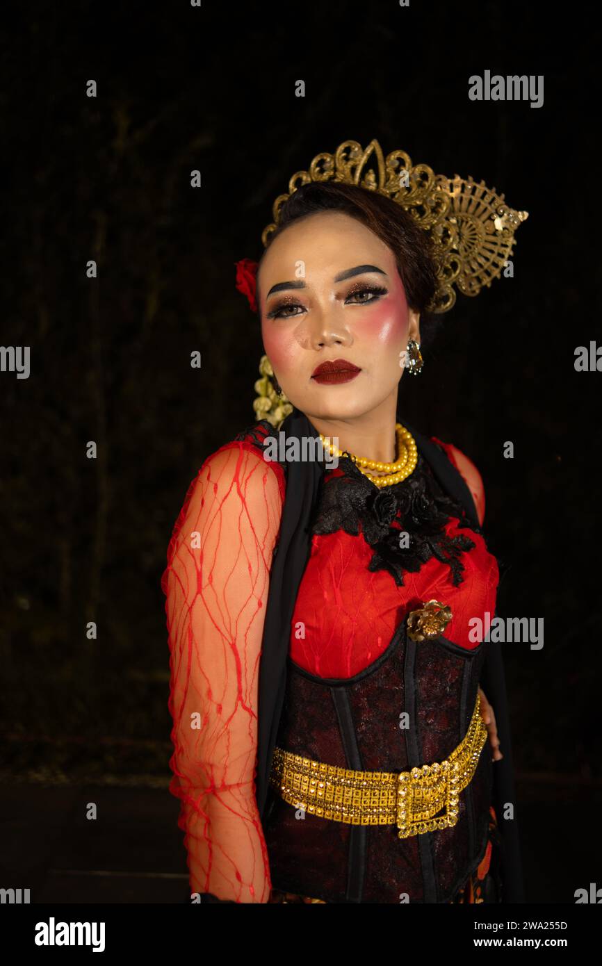 Una ballerina sundanese che indossa gioielli d'oro che dona un tocco di lusso al suo aspetto sul palco di notte Foto Stock