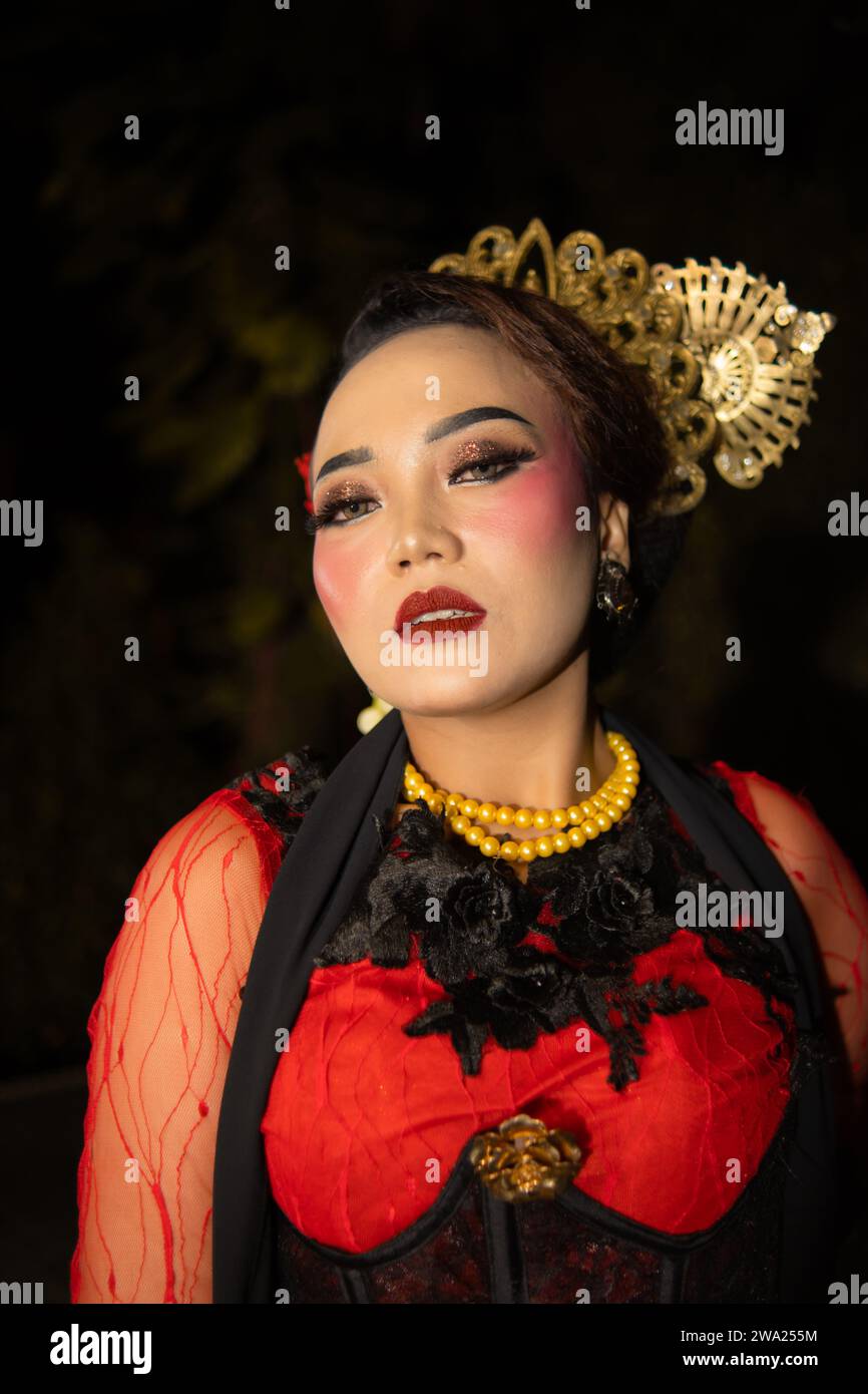 Una ballerina sundanese che indossa gioielli d'oro che dona un tocco di lusso al suo aspetto sul palco di notte Foto Stock
