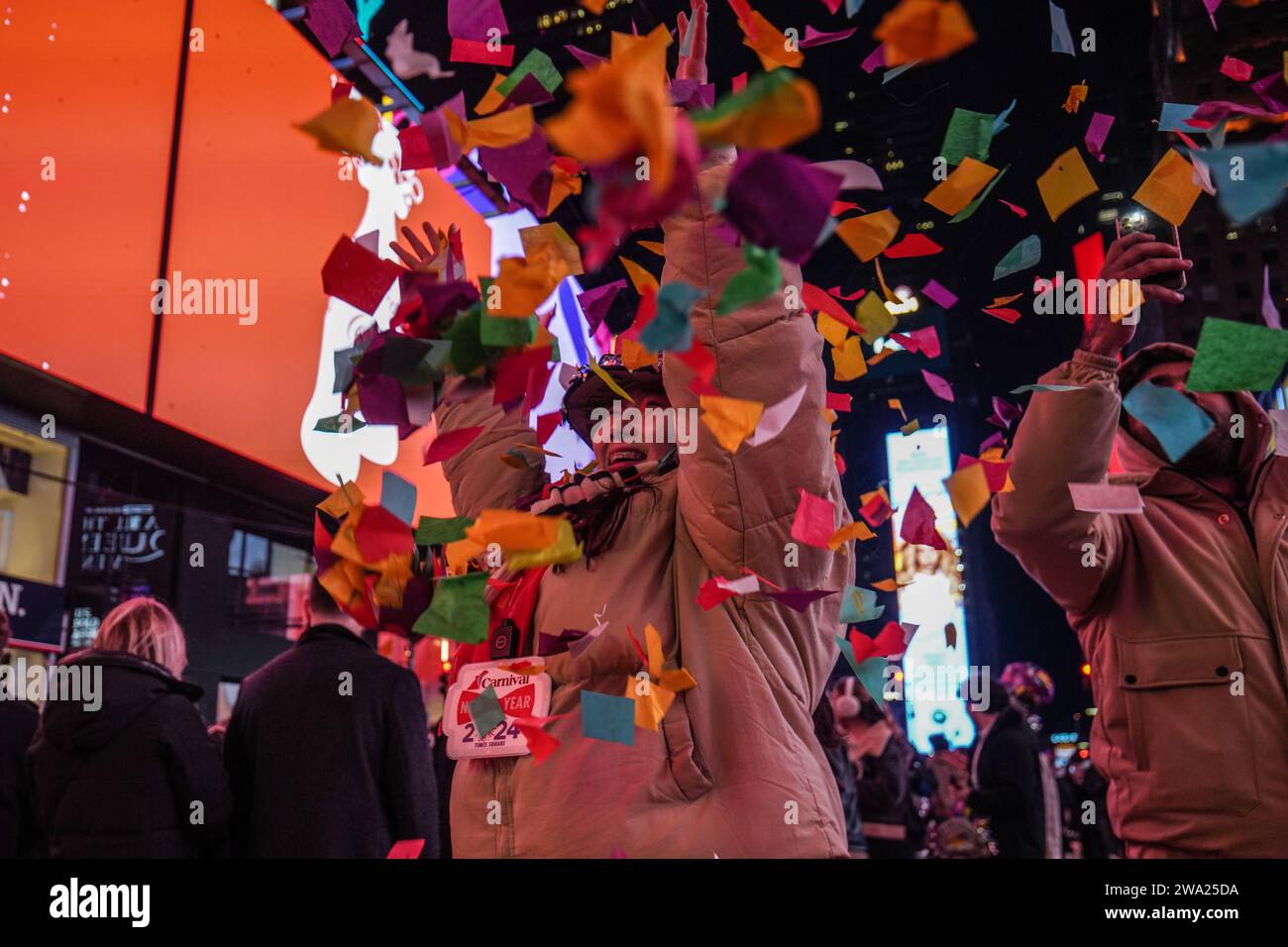 New York, USA. 31 dicembre 2023. Una ragazza si diverte con la carta colorata mentre i coriandoli cadono dal cielo. La celebrazione del Capodanno 2024 di Times Square a New York City segna un ritorno monumentale dopo la pandemia di COVID-19, attirando migliaia di persone entusiaste a partecipare all'iconico conto alla rovescia e ad accogliere il nuovo anno. Come la tradizione vuole, la scintillante caduta della palla cattura la folla, segnalando il passaggio al 2024. Credito: SOPA Images Limited/Alamy Live News Foto Stock