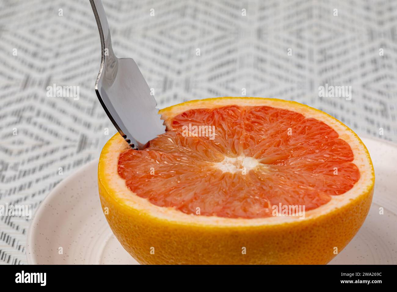 Pompelmo affettato su piatto con cucchiaio seghettato. Frutta biologica, dieta sana e concetto nutrizionale. Foto Stock