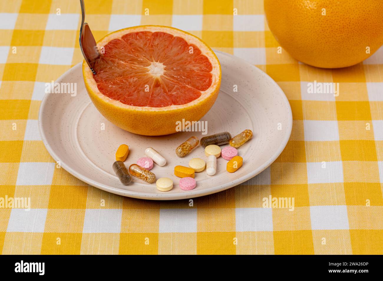 Pompelmo tagliato su piatto con vitamine e integratori alimentari. Frutta biologica, dieta sana e concetto nutrizionale. Foto Stock