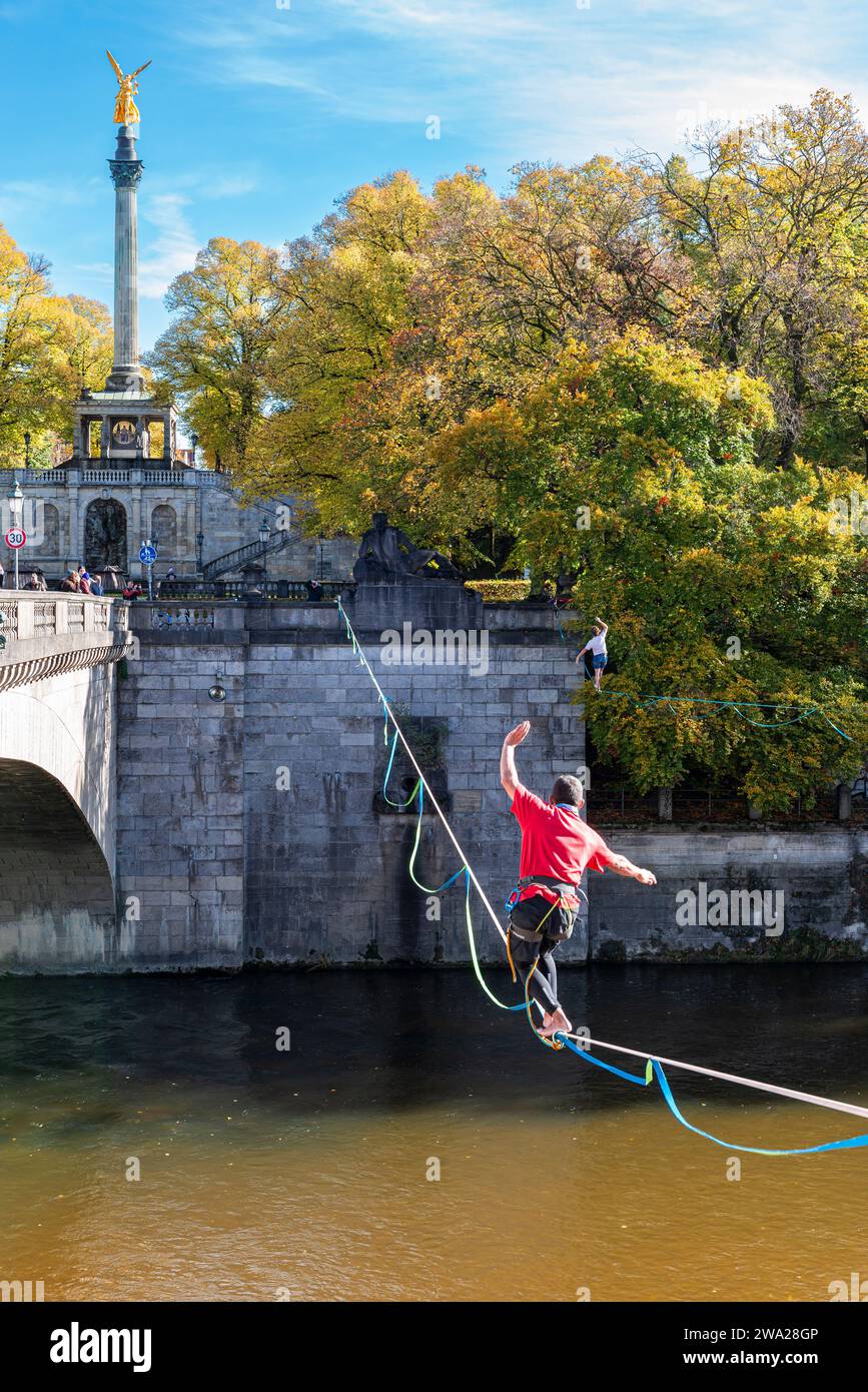 Due uomini che si bilanciano sulle slackline dell'Isar al ponte Luitpold nel sole autunnale, Monaco, Baviera, Germania Foto Stock