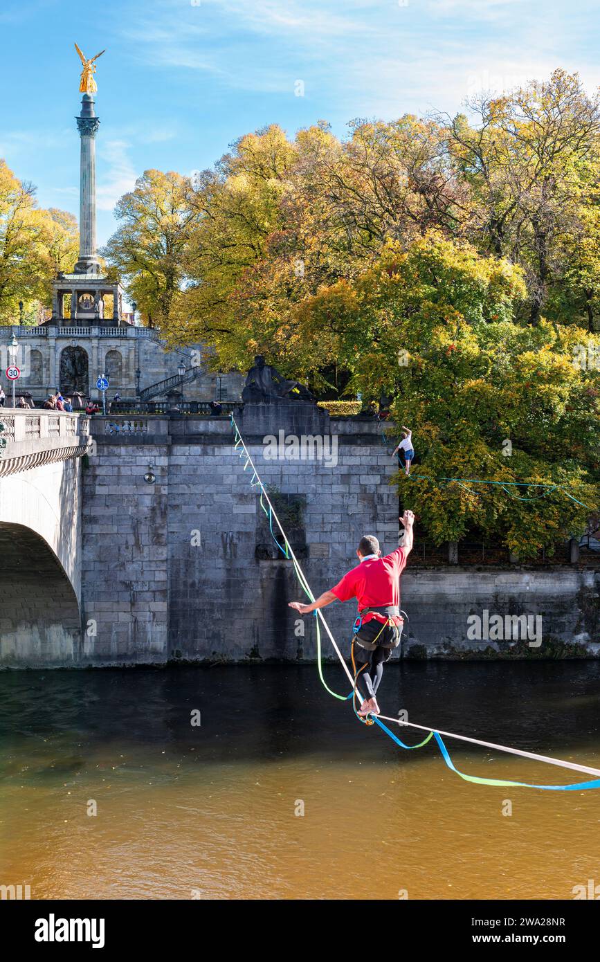 Due uomini che si bilanciano sulle slackline dell'Isar al ponte Luitpold nel sole autunnale, Monaco, Baviera, Germania Foto Stock