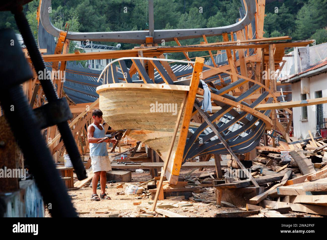 Un uomo costruisce una barca di legno in un cantiere vicino a Fethiye, in Turchia Foto Stock