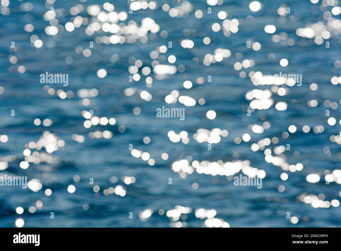 Evidenziazioni sfocate o effetto bokeh sull'acqua blu come sfondo Foto Stock