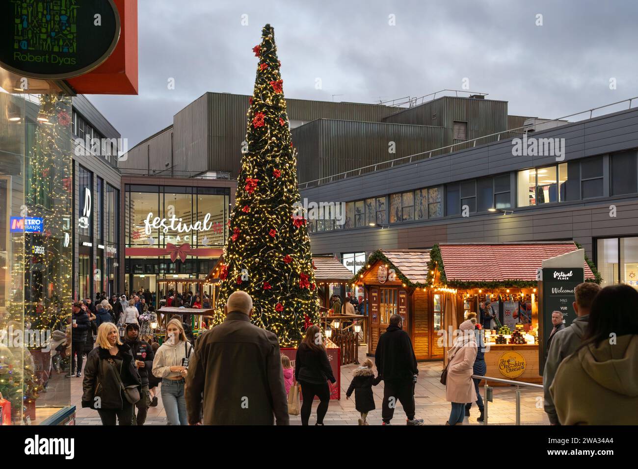 Negozi natalizi, bancarelle del mercato e albero di Natale presso il centro commerciale Malls di fronte al Festival Place al tramonto. Basingstoke, Regno Unito Foto Stock
