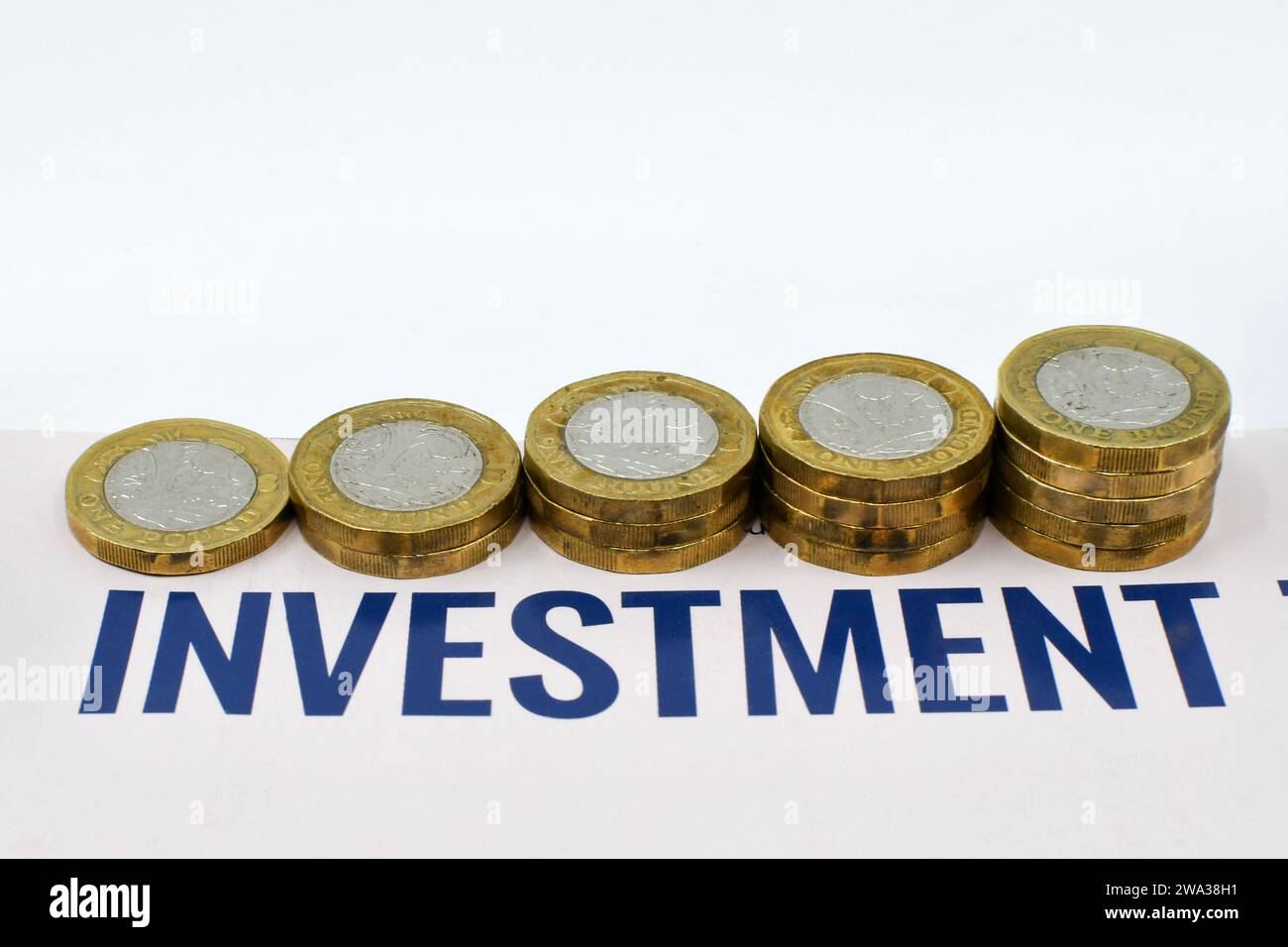 Monete britanniche da una sterlina in colonne di dimensioni crescenti accanto a un documento di investimento. Niente persone. Foto Stock