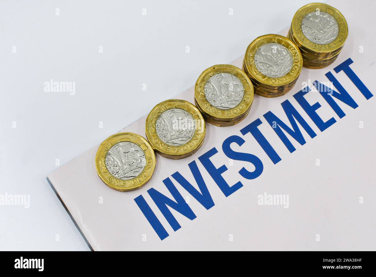 Monete britanniche da una sterlina in colonne di dimensioni crescenti accanto a un documento di investimento. Niente persone. Foto Stock
