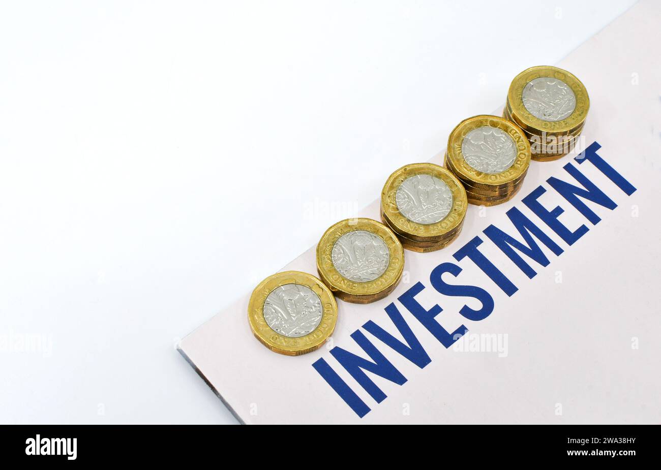 Monete britanniche da una sterlina in colonne di dimensioni crescenti accanto a un documento di investimento. Niente persone. Foto Stock