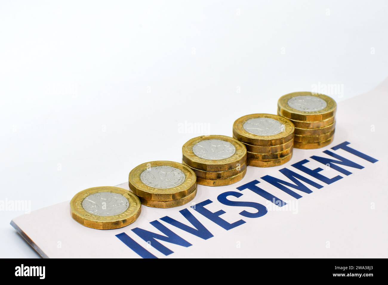 Monete britanniche da una sterlina in colonne di dimensioni crescenti accanto a un documento di investimento. Niente persone. Foto Stock