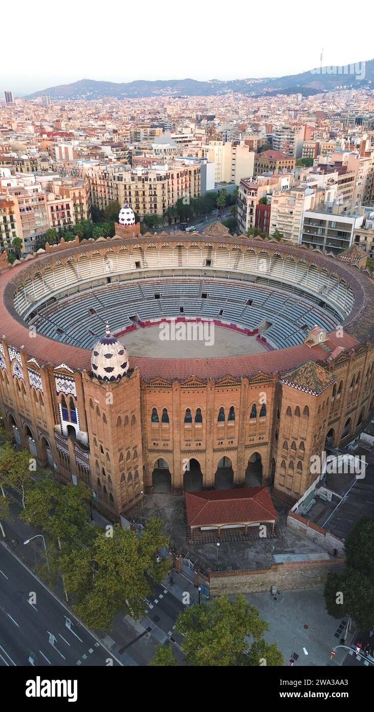 Riprese aeree con drone di La Monumental Barcellona Spagna storica arena di corride neo-mudejar con cupole rivestite di mattonelle griglia del distretto Eixample e skyline della città Foto Stock