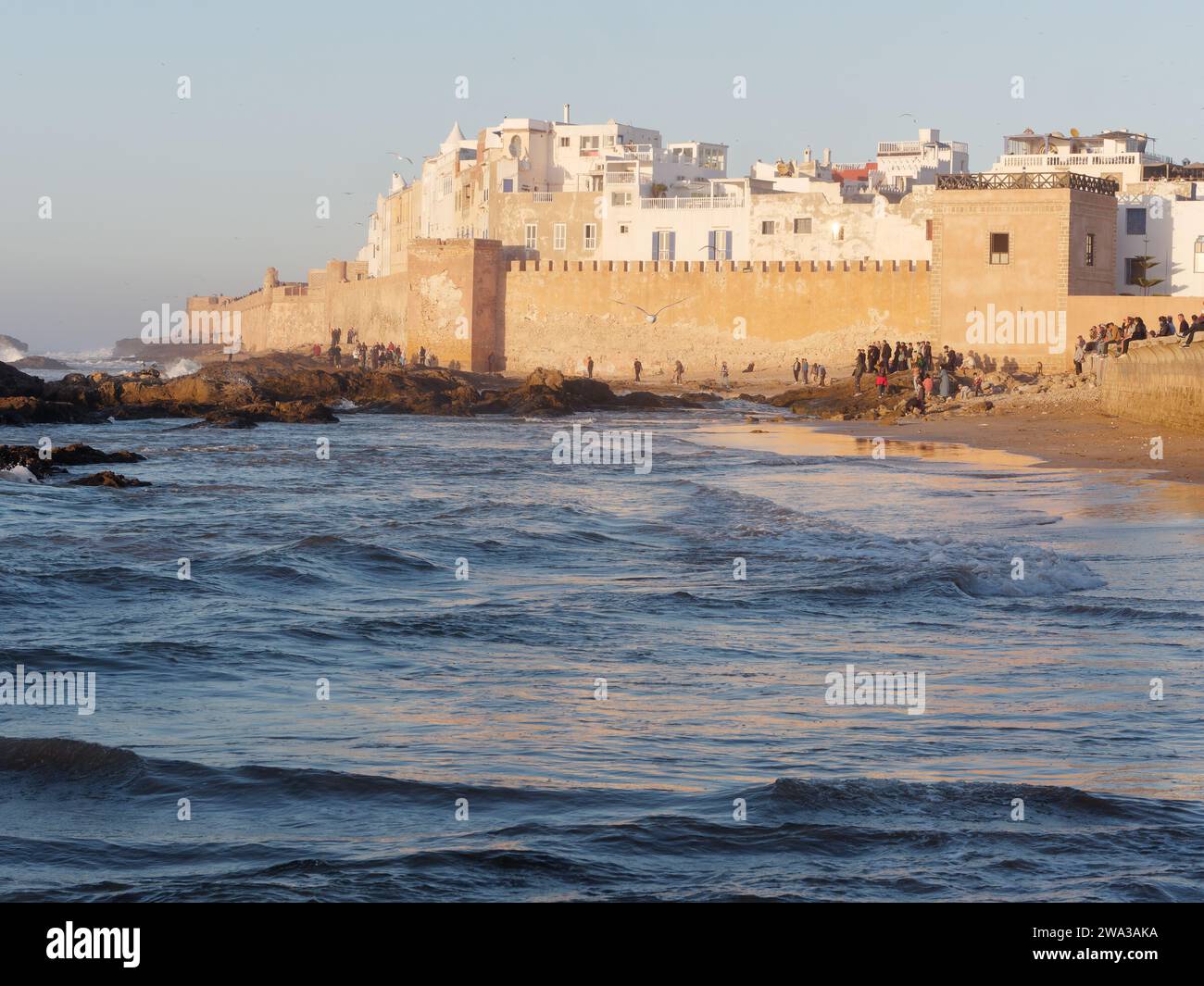 Spiaggia rocciosa con le mura della citta' e la storica medina dietro nella citta' di Essaouira in una serata d'inverno, Marocco, 1 gennaio 2024 Foto Stock