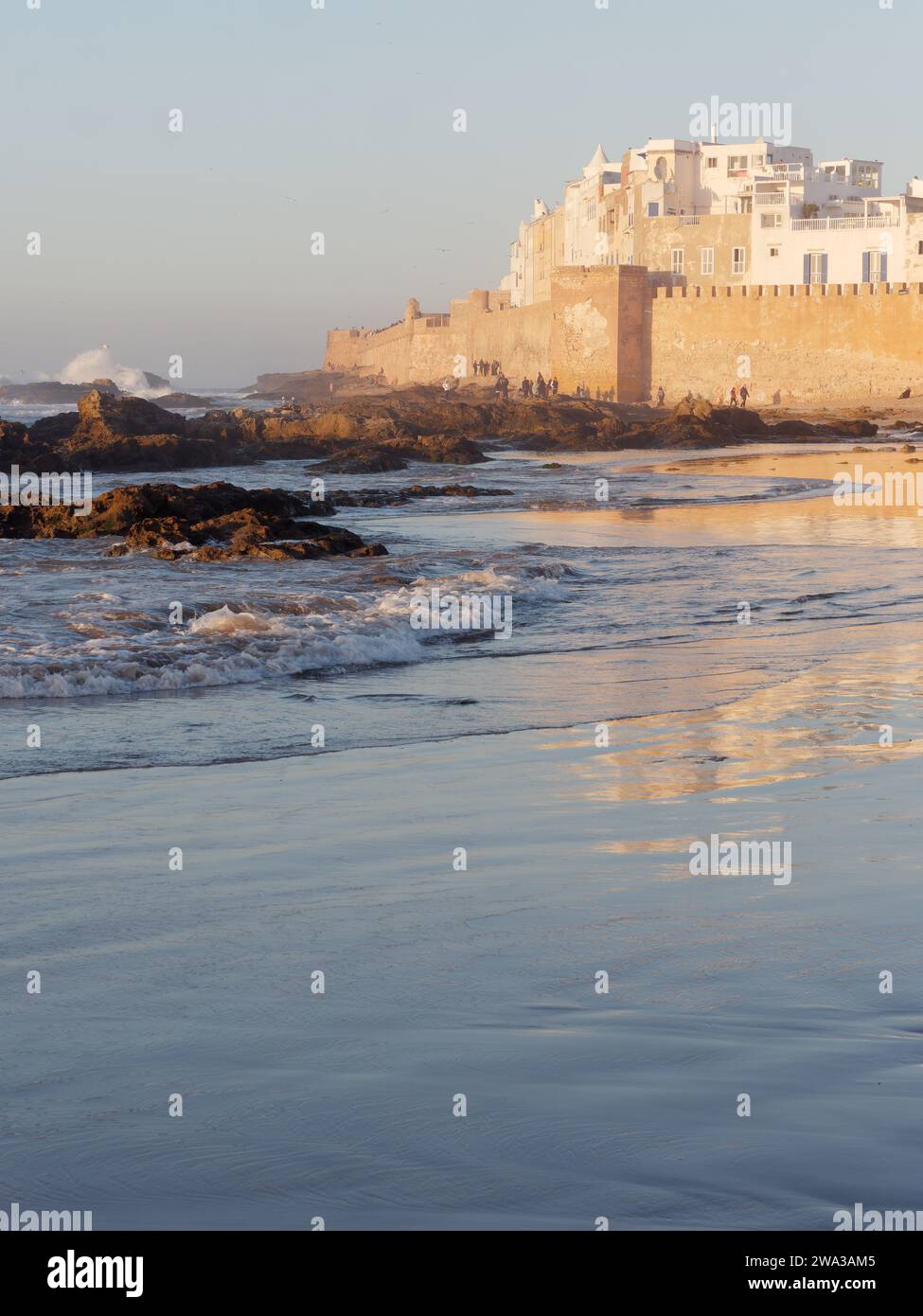 Spiaggia rocciosa con le mura della citta' e la storica medina dietro nella citta' di Essaouira in una serata d'inverno, Marocco, 1 gennaio 2024 Foto Stock