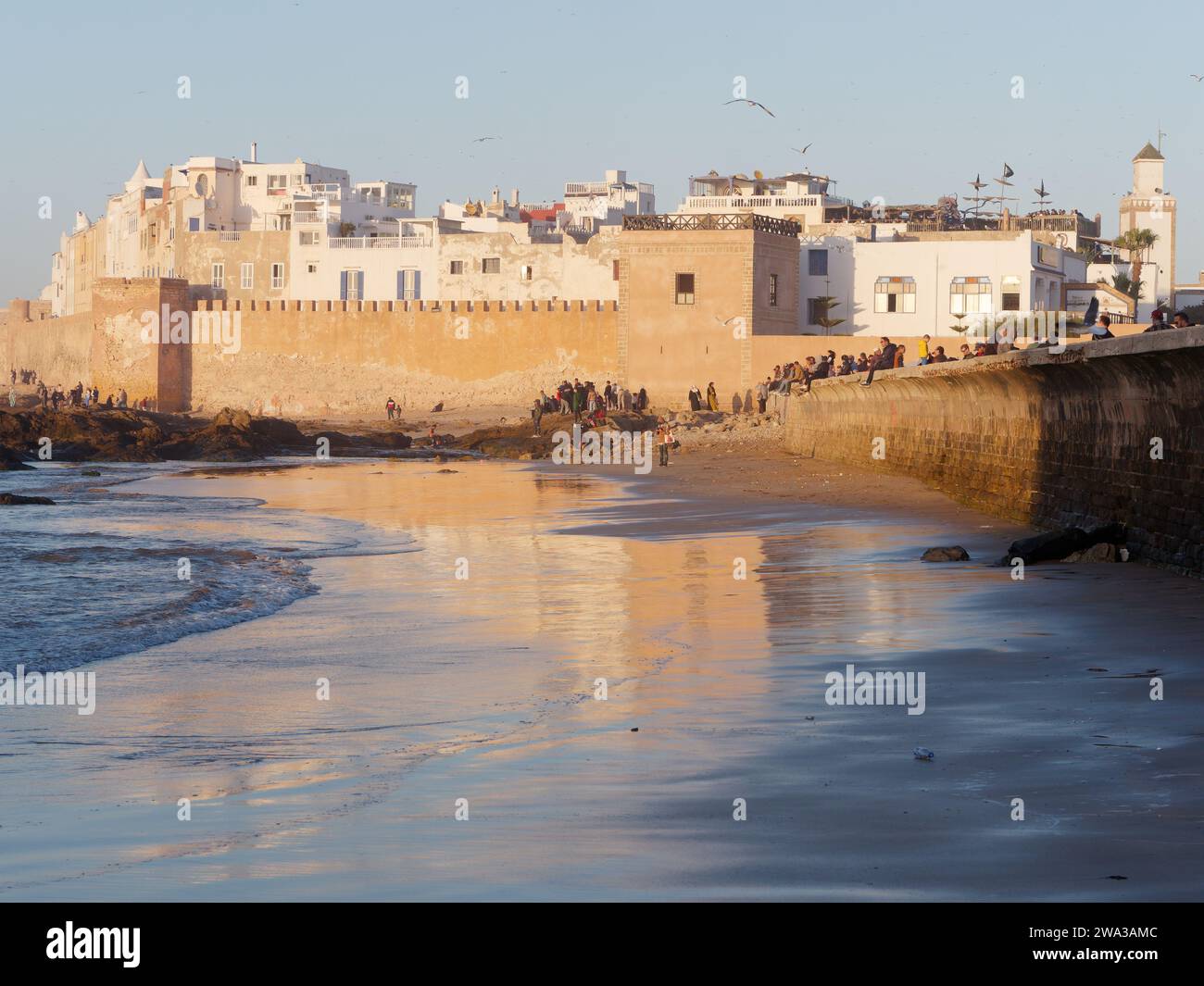 Spiaggia rocciosa con le mura della citta' e la storica medina dietro nella citta' di Essaouira in una serata d'inverno, Marocco, 1 gennaio 2024 Foto Stock