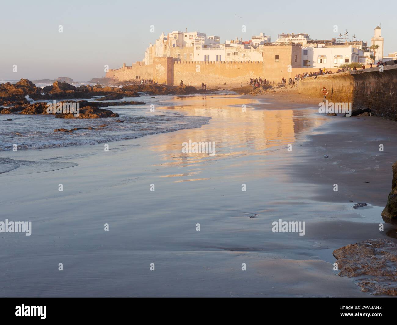 Spiaggia rocciosa con le mura della citta' e la storica medina dietro nella citta' di Essaouira in una serata d'inverno, Marocco, 1 gennaio 2024 Foto Stock