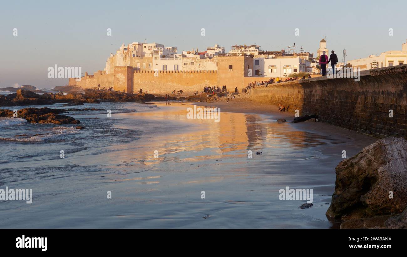 Spiaggia rocciosa con le mura della citta' e la storica medina dietro nella citta' di Essaouira in una serata d'inverno, Marocco, 1 gennaio 2024 Foto Stock