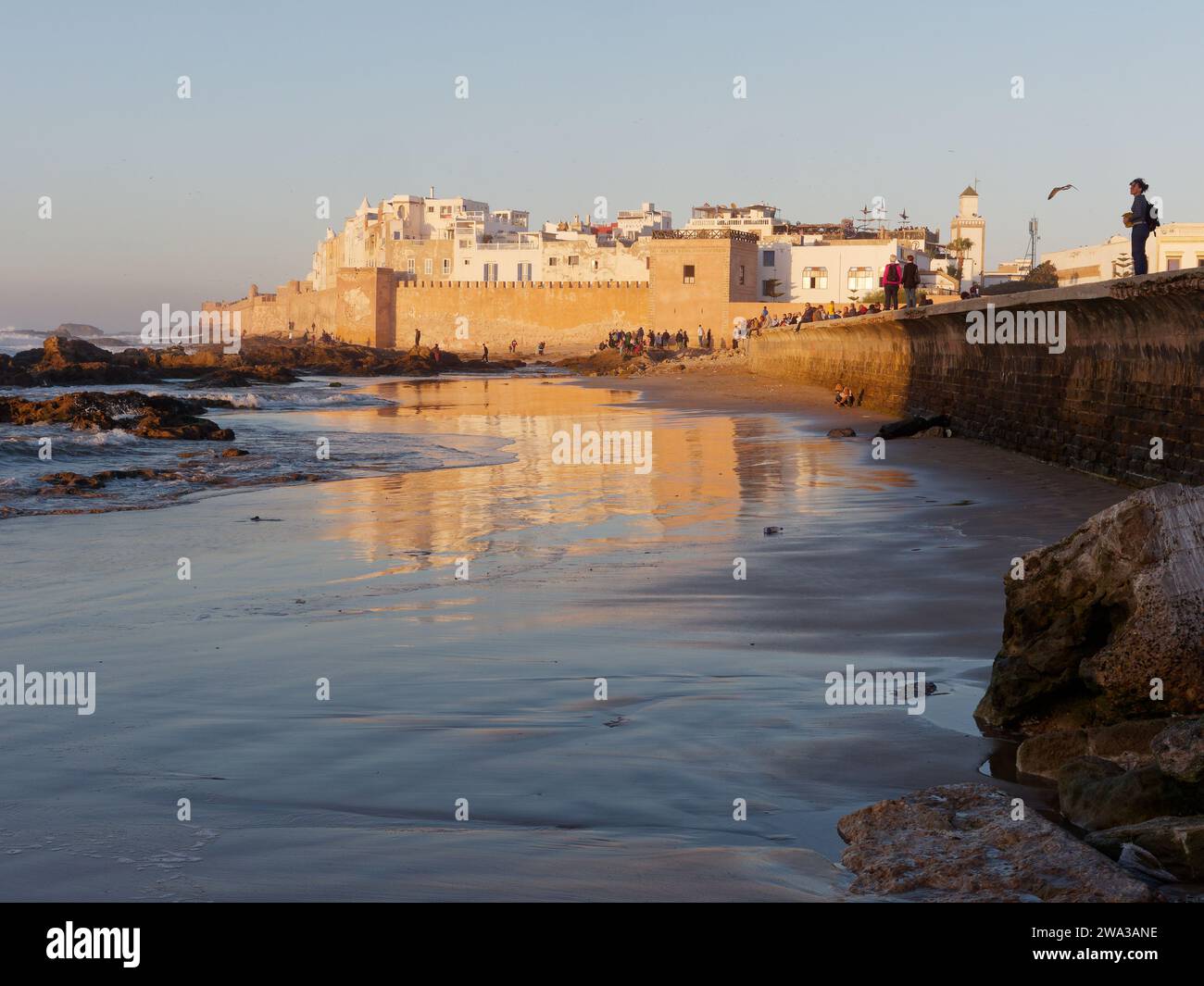 Spiaggia rocciosa con le mura della citta' e la storica medina dietro nella citta' di Essaouira in una serata d'inverno, Marocco, 1 gennaio 2024 Foto Stock