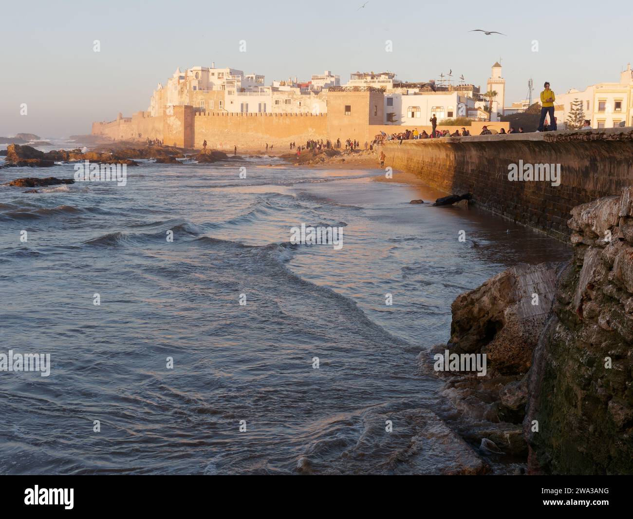 Spiaggia rocciosa con le mura della citta' e la storica medina dietro nella citta' di Essaouira in una serata d'inverno, Marocco, 1 gennaio 2024 Foto Stock