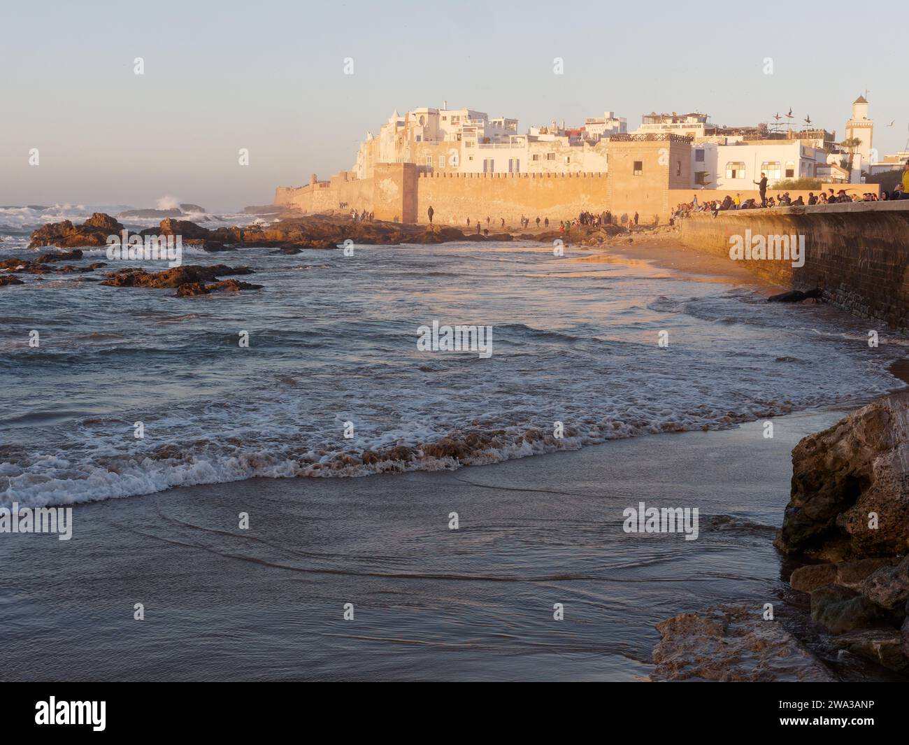 Spiaggia rocciosa con le mura della citta' e la storica medina dietro nella citta' di Essaouira in una serata d'inverno, Marocco, 1 gennaio 2024 Foto Stock