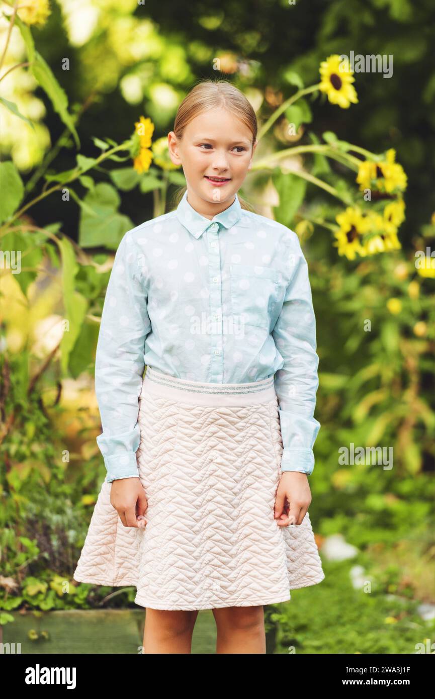 Ritratto alla moda di una graziosa bambina all'aperto, che indossa una camicia verde chiaro e una gonna rosa Foto Stock