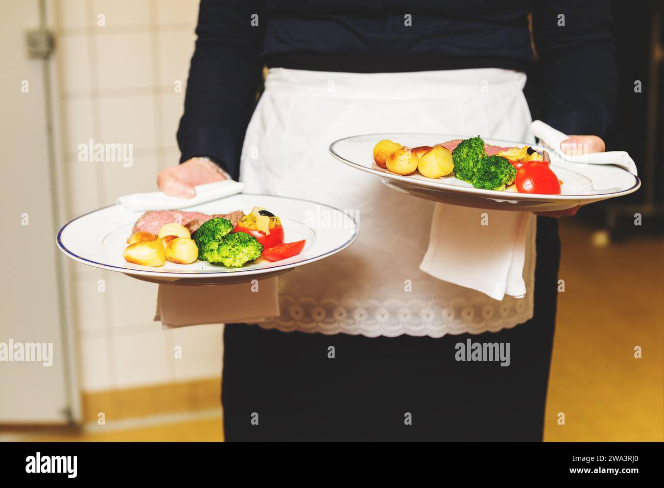 Cameriere portante due piastre con piatto di carne su qualche evento festivo, party, ricevimento di matrimonio o evento di catering Foto Stock