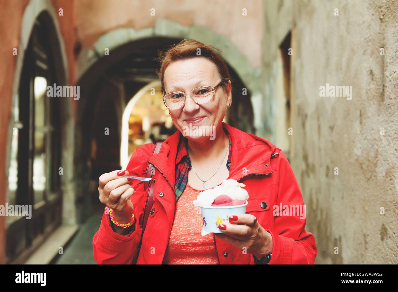 donna di 50-60 anni che mangia gelati all'aperto Foto Stock