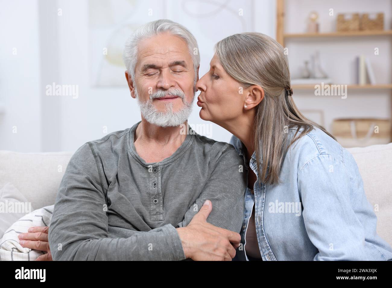 Donna anziana che bacia il suo amato uomo a casa Foto Stock