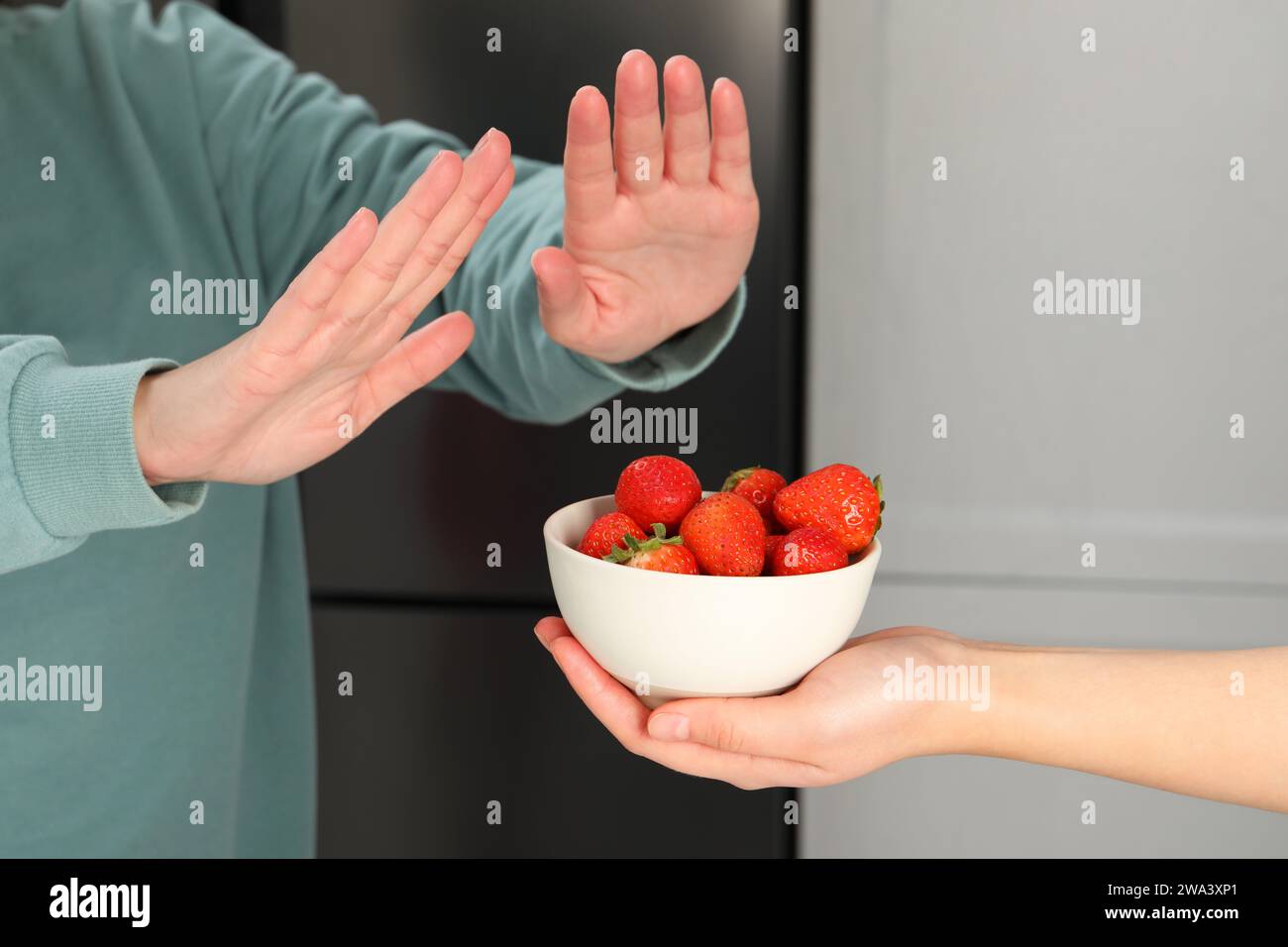 Donna che soffre di allergie alimentari che rifiuta di offrire fragole dal suo amico a casa, primo piano Foto Stock