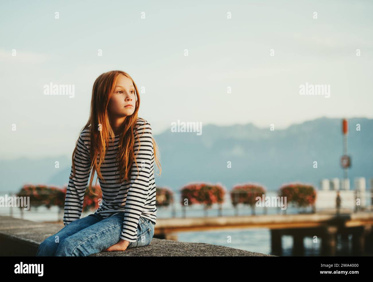 Graziosa bambina dai capelli rossi che riposa sul lago di Ginevra al tramonto, immagine scattata a Losanna, in Svizzera Foto Stock