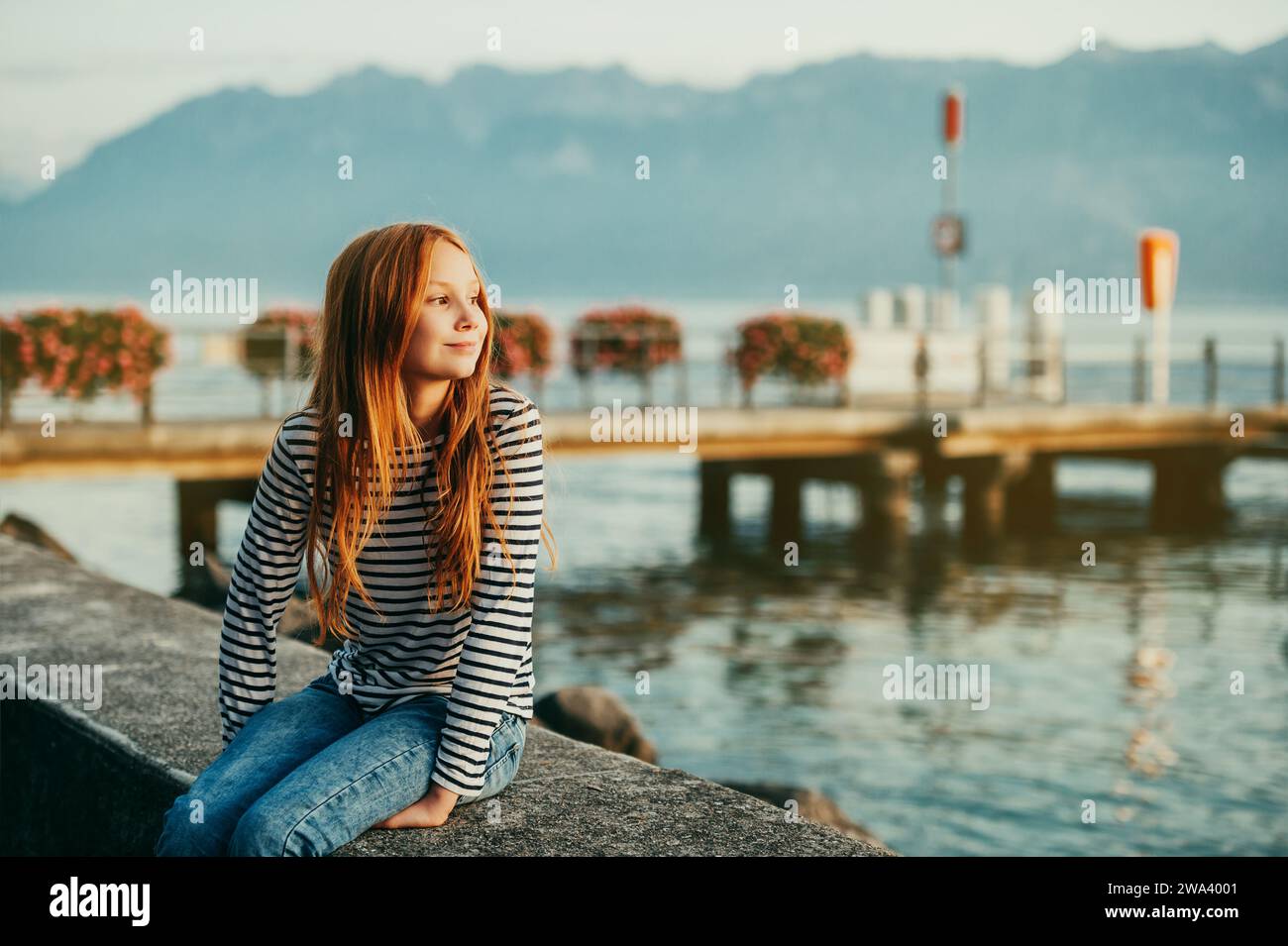 Graziosa bambina dai capelli rossi che riposa sul lago di Ginevra al tramonto, immagine scattata a Losanna, in Svizzera Foto Stock