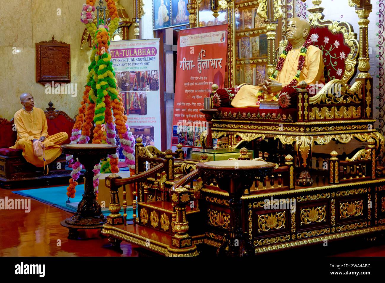 Una statua realistica del fondatore dell'ISKCON Bhaktivedanta Swami Prabhupada al Tempio Sri Radha Gopinath a Girgaum, Mumbai, India; a sinistra: Un monaco ISKCON Foto Stock