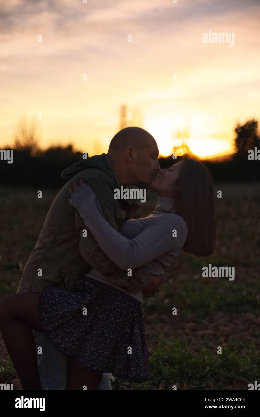 Un uomo abbraccia e bacia la sua ragazza al tramonto in un ambiente naturale. Foto Stock