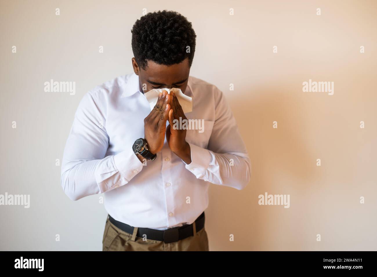 Ritratto di un giovane uomo d'affari allergico e che soffia il naso. Spazio di copia sull'immagine per il testo o l'annuncio pubblicitario. Foto Stock