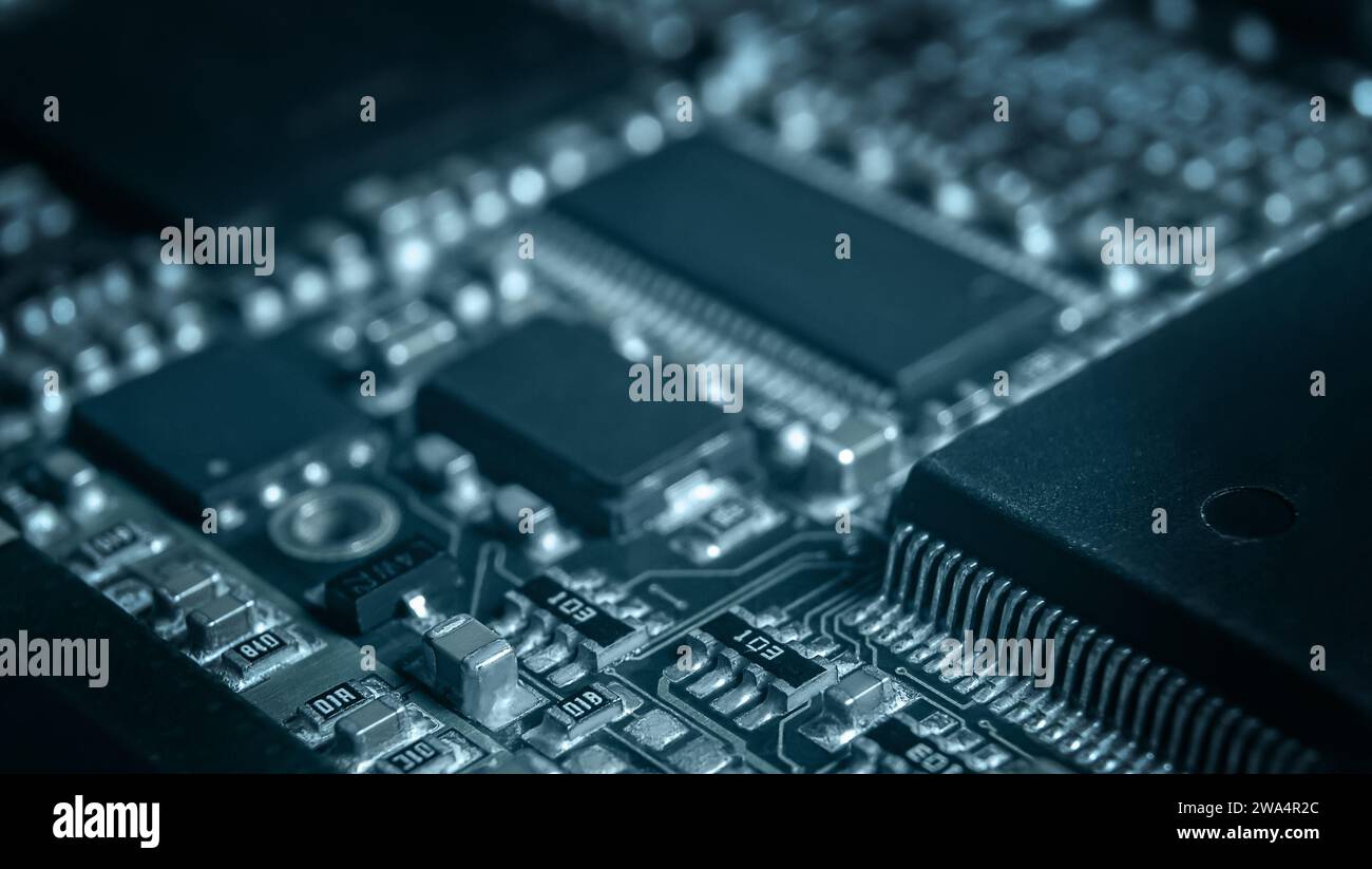Primo piano sulla moderna scheda elettronica con processore, circuiti integrati e componenti passivi a montaggio superficiale. Background tecnologico Foto Stock