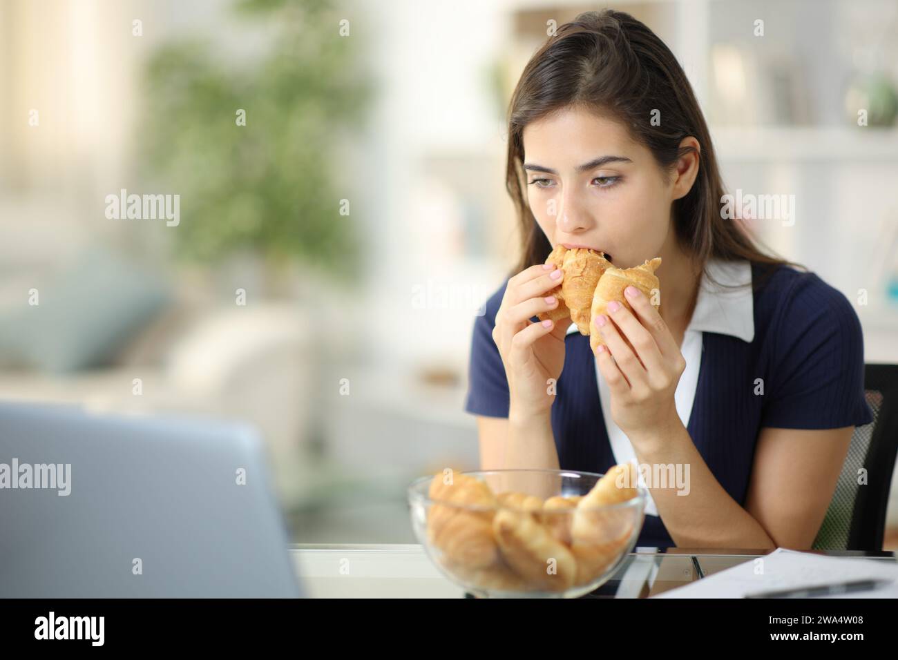 Scoraggiata donna ansiosa che mangia panetteria cercando di alleviare l'ansia a casa Foto Stock
