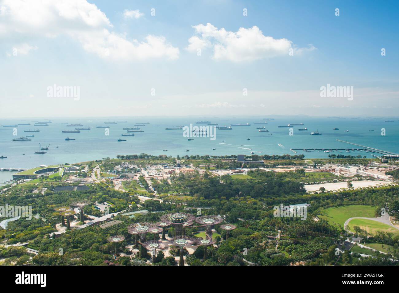 Una vista dalla piattaforma di osservazione di Marina Bay Sands di Gardens by the Bay e dalle navi cargo e merci nello stretto di Singapore Foto Stock