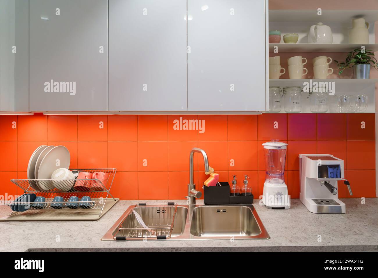 Immagini degli interni della cucina con un elegante lavandino, un'area piatti ben organizzata, una sofisticata macchina per il caffè e un elegante bancone, questa scena incarna la p Foto Stock