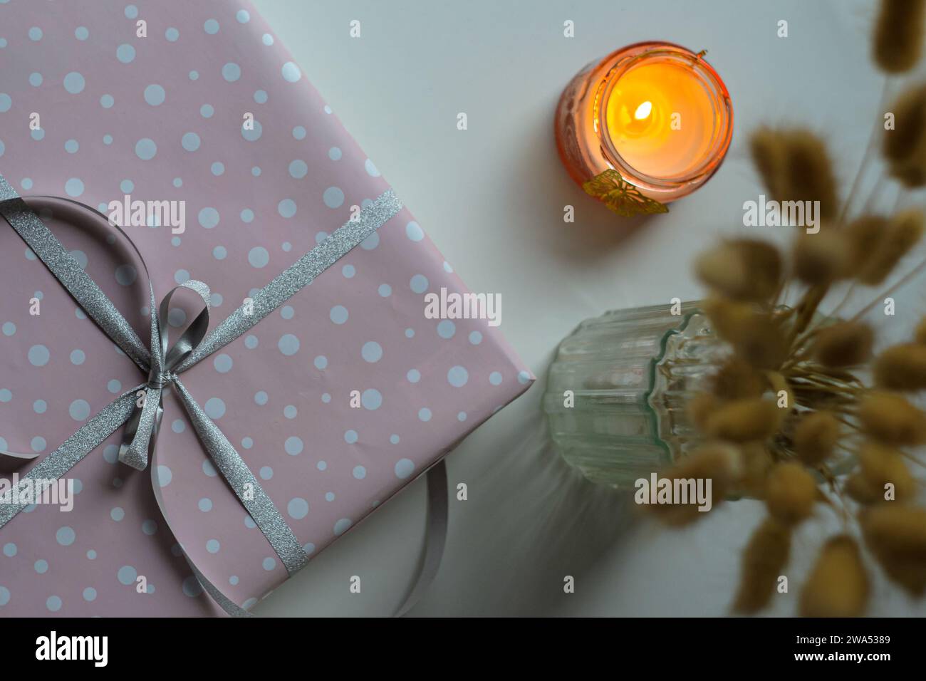 Regalo natalizio avvolto con candela in fiamme e fiori in vaso Foto Stock